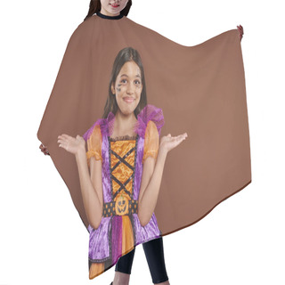 Personality  Confused Girl In Halloween Costume With Spiderweb Makeup Smiling And Gesturing On Brown Backdrop Hair Cutting Cape