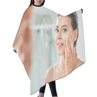 Personality  Selective Focus Of Smiling Young Woman Applying Face Cream And Looking At Mirror In Bathroom  Hair Cutting Cape