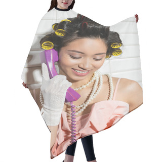 Personality  Happy And Asian Young Woman With Hair Curlers Standing In Pink Ruffled Top, Pearl Necklace And White Gloves And Talking On Purple Retro Phone And Smiling Near White Tiles, Housewife  Hair Cutting Cape