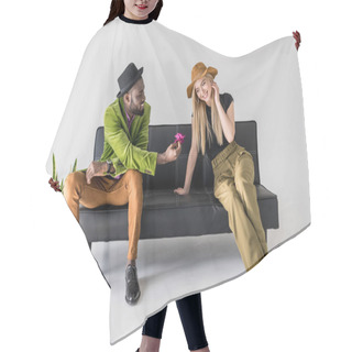 Personality  African American Fashionable Man Presenting Flower To Smiling Caucasian Girlfriend On Black Sofa Hair Cutting Cape