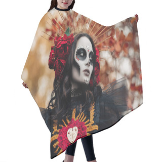Personality  Portrait Of Young Woman With Sugar Skull Makeup And Red Roses Dressed In Black Costume Of Death As Santa Muerte Against Background Of Autumn Leaves In Forest. Day Of The Dead Or Halloween Concept. Hair Cutting Cape