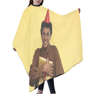 Personality  Cheerful African American Teenage Boy In Party Cap Holding Present Isolated On Yellow Hair Cutting Cape