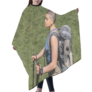 Personality  Young Short Haired And Tattooed Female Hiker With Backpack And Fitness Tracker Holding Trekking Poles And Walking On Grassy Lawn At Background, Solo Hiking Journey Concept, Summer Hair Cutting Cape
