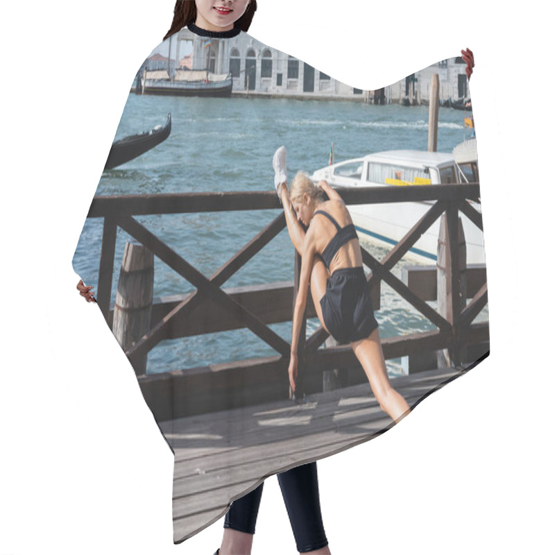 Personality  Side View Of Blonde Sportswoman In White Sneakers, Black Crop Top And Shorts Stretching On Pier In Italy  Hair Cutting Cape