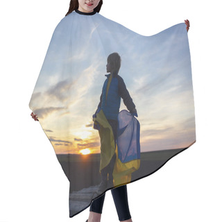 Personality  Silhouette Of A Sad Boy Holding Ukrainian Flag Against Backdrop Of Bright Beautiful Sunset Sky. Children Against War. Stop Russian Aggression. The Concept Of Patriotism And Love For The Motherland Hair Cutting Cape