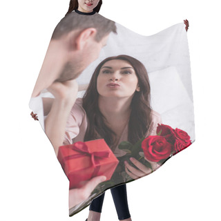 Personality  Woman With Flowers Pouting Lips Near Husband With Present On Blurred Foreground In Bedroom  Hair Cutting Cape