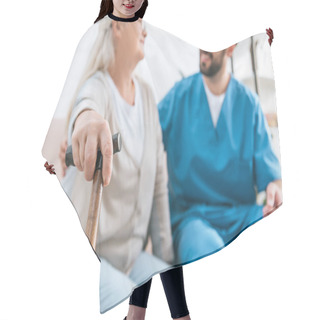 Personality  Close-up View Of Senior Woman Holding Walking Cane And Looking At Smiling Male Nurse  Hair Cutting Cape