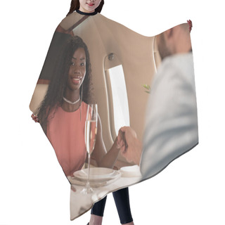 Personality  Selective Focus Of Elegant African American Girl Looking At Camera While Holding Hands With Man At Served Table In Private Plane Hair Cutting Cape