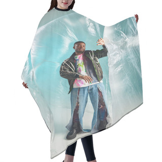 Personality  Full Length Of Trendy Young African American Man In Ripped Jeans And Outwear Jacket Looking Away Near Glossy Cellophane On Turquoise Background, Urban Outfit, Creative Expression, DIY Clothing  Hair Cutting Cape