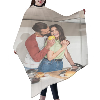 Personality  Man Holding Fresh Apple Near Smiling Girlfriend And Pancakes In Kitchen  Hair Cutting Cape