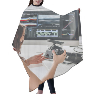 Personality  Editor Holding Digital Camera Near Table With Computer Monitors  Hair Cutting Cape