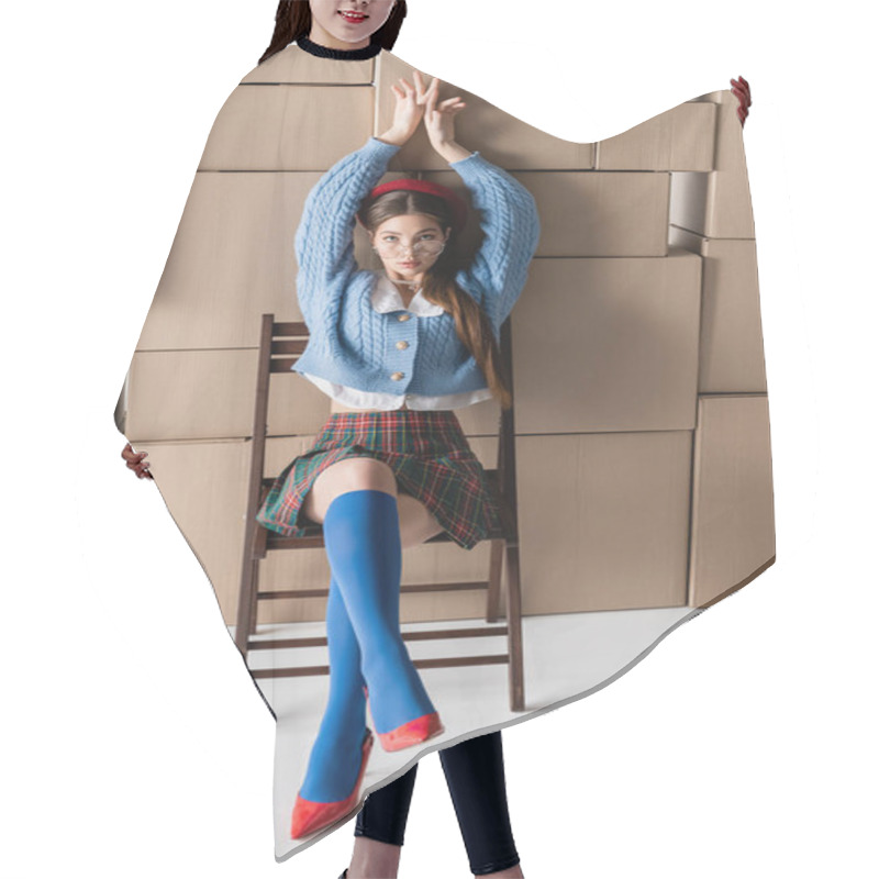 Personality  Trendy Model In Beret And Eyeglasses Posing While Sitting On Chair Near Cardboard Boxes On White Background  Hair Cutting Cape