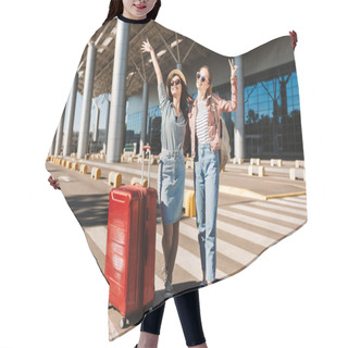 Personality  Two Cheerful Female Friends In Sunglasses Happily Looking In Camera Raising Hands Up With Red Suitcase And Backpack On Shoulder Outdoor Near Airport Hair Cutting Cape