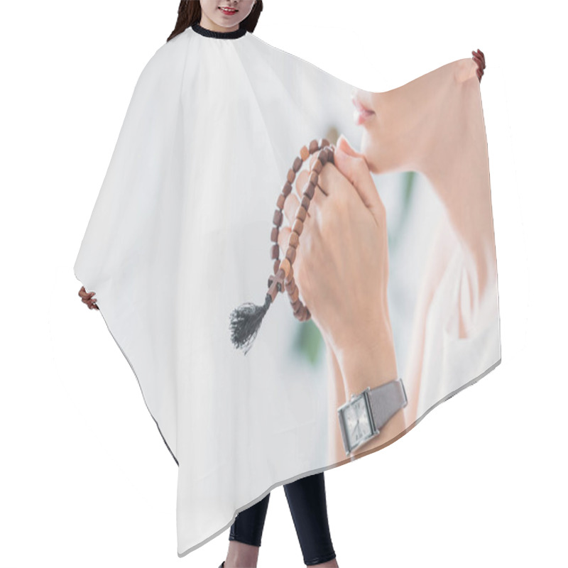 Personality  cropped view of woman praying with wooden rosary beads hair cutting cape