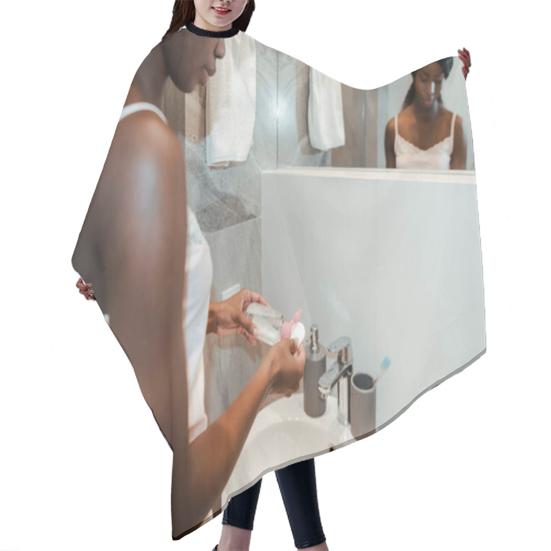 Personality  Cropped View Of African American Woman Holding Bottle Of Skin Toner Near Mirror In Bathroom Hair Cutting Cape