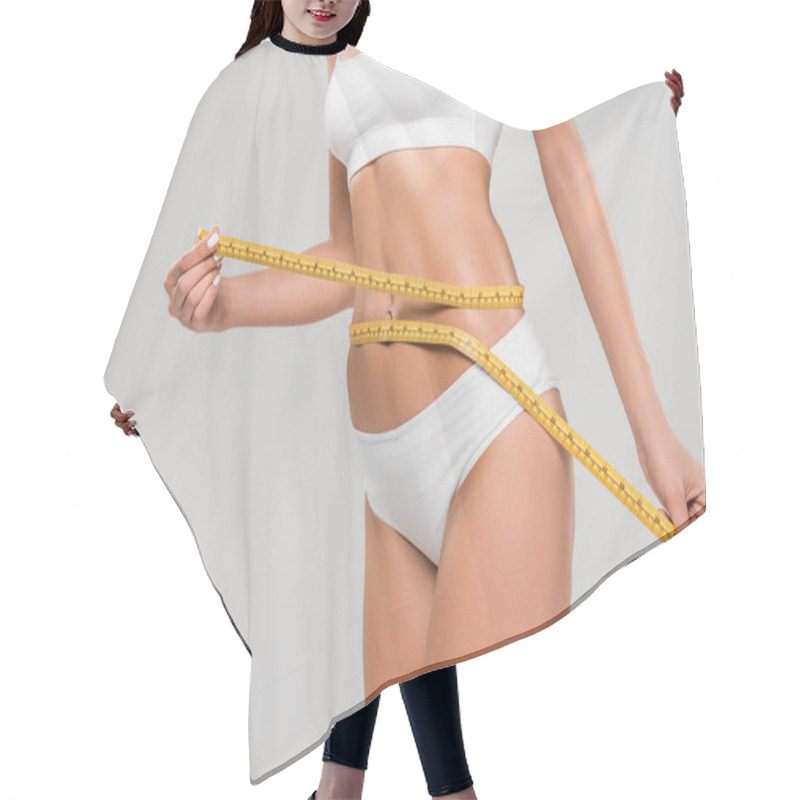 Personality  partial view of beautiful slim woman in underwear holding measuring tape on waist isolated on grey hair cutting cape