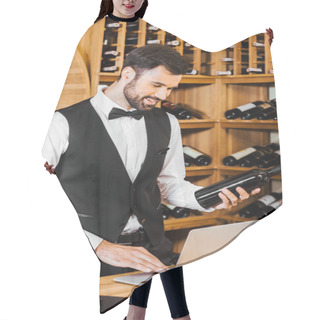 Personality  Smiling Young Sommelier With Bottle Of Wine Making Notes At Wine Store Hair Cutting Cape