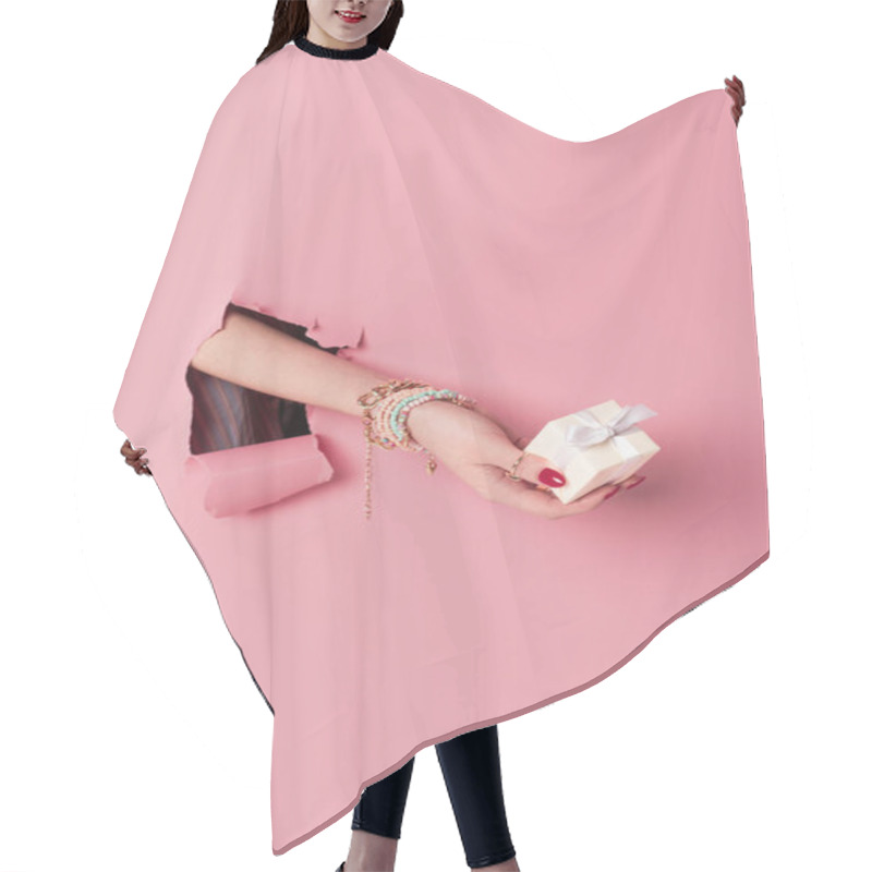 Personality  Cropped view of young woman holding present pink background with hole  hair cutting cape