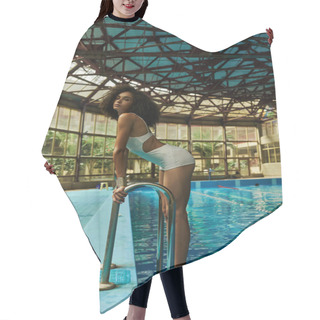 Personality  Young And Curly African American Woman In Bathing Suit Standing By Pool Ladder With Blue Water Hair Cutting Cape