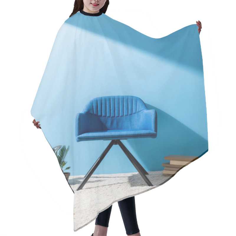 Personality  comfy blue armchair with person holding cup of coffee on floor in front of blue wall hair cutting cape