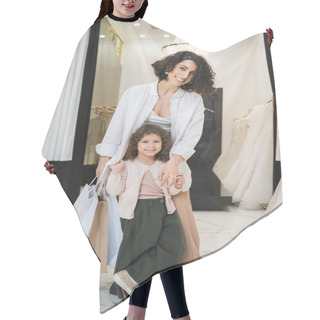 Personality  Joyful Middle Eastern Woman With Brunette Hair Holding Shopping Bags And Hugging Cute Little Girl While Standing Near White Wedding Dresses In Bridal Salon, Mother And Daughter, Bridal Shopping  Hair Cutting Cape
