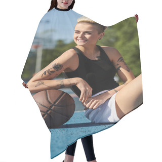 Personality  A Young Woman With Short Hair And Tattoos Sits On The Ground, Holding A Basketball In An Urban Outdoor Setting. Hair Cutting Cape