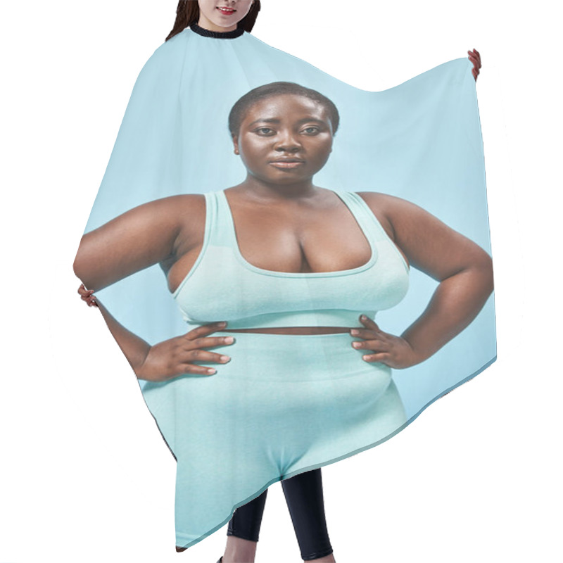 Personality  Strong Plus Size African American Woman In Blue Sportswear With Hands On Hips On Matching Backdrop Hair Cutting Cape