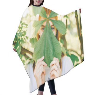 Personality  Obscured View Of Young Red Hair Woman Looking At Camera Behind Chestnut Leaf In Park Hair Cutting Cape
