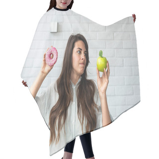 Personality  Young Student Woman Doubts What To Choose Healthy Food Or Sweets Junk Unhealthy Food Holding Green Apple And Donut In Hands Standing At Home In Her Living Room. Hard Choice Concept Hair Cutting Cape