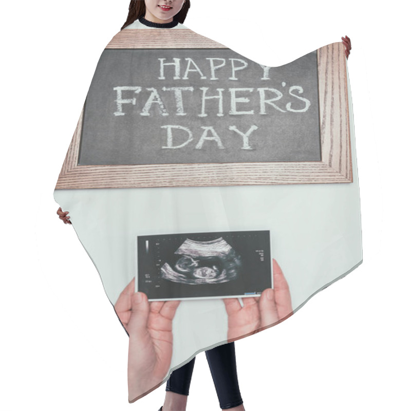 Personality  cropped shot of woman with ultrasound scan in hands and happy fathers day blackboard isolated on grey hair cutting cape