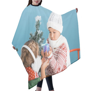 Personality  Selective Focus Of Boy In Knitted Hat Holding Present While Sitting On Sleight Near Girl In Winter Earmuffs On Blue Hair Cutting Cape