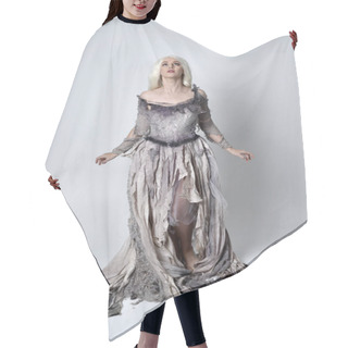 Personality  Full Length Portrait Of Blonde Girl Wearing Long Torn Old Wedding Dress.  Standing Pose With Back To The Camera On A Studio Background. Hair Cutting Cape