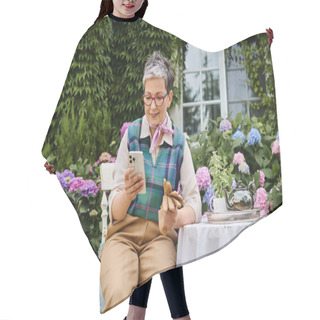 Personality  Mature Cheerful Woman Sitting In Garden At Tea Time And Looking At Phone Near House In England Hair Cutting Cape