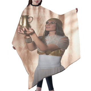 Personality  Elegant Woman In Egyptian Attire And Pearl Top Looking At Golden Jug On Abstract Background Hair Cutting Cape