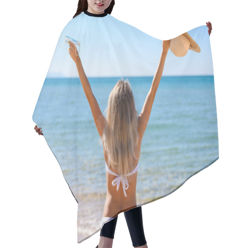 Personality  A girl in a white bathing suit stands by the sea with her arms r hair cutting cape