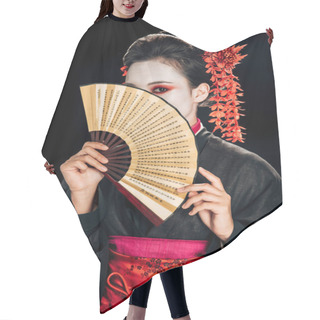 Personality  Geisha In Black Kimono With Red Flowers In Hair And Obscure Face Holding Traditional Asian Hand Fan Isolated On Black Hair Cutting Cape