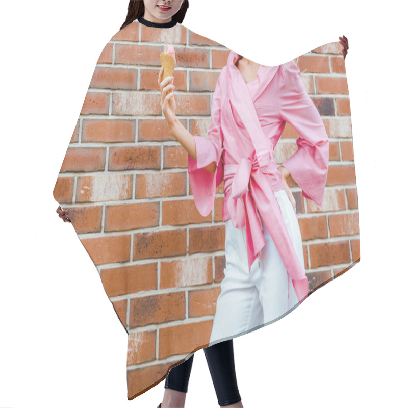 Personality  cropped shot of young woman in pink holding ice cream in front of brick wall hair cutting cape