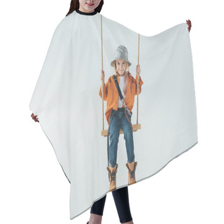 Personality  Cute Kid In Silver Hat, Jeans And Orange Shirt Sitting On Swing On Grey Background  Hair Cutting Cape