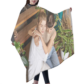 Personality  Two Women Hugging In Front Of Lush Plants At An Art Studio. Hair Cutting Cape