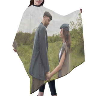 Personality  Bearded And Stylish Man In Jacket And Newsboy Cap Holding Hand And Looking At Cheerful Girlfriend In Vest And Standing Together On Grassy Lawn At Overcast, Stylish Couple In Rural Setting Hair Cutting Cape