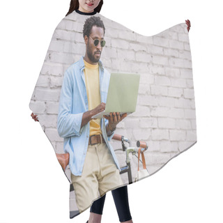 Personality  Attentive, Stylish African American Man Using Laptop While Standing By Brick Wall Near Bicycle Hair Cutting Cape