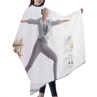 Personality  Middle Aged Woman In Sportwear Standing In Warrior Pose While Practicing Yoga At Home  Hair Cutting Cape