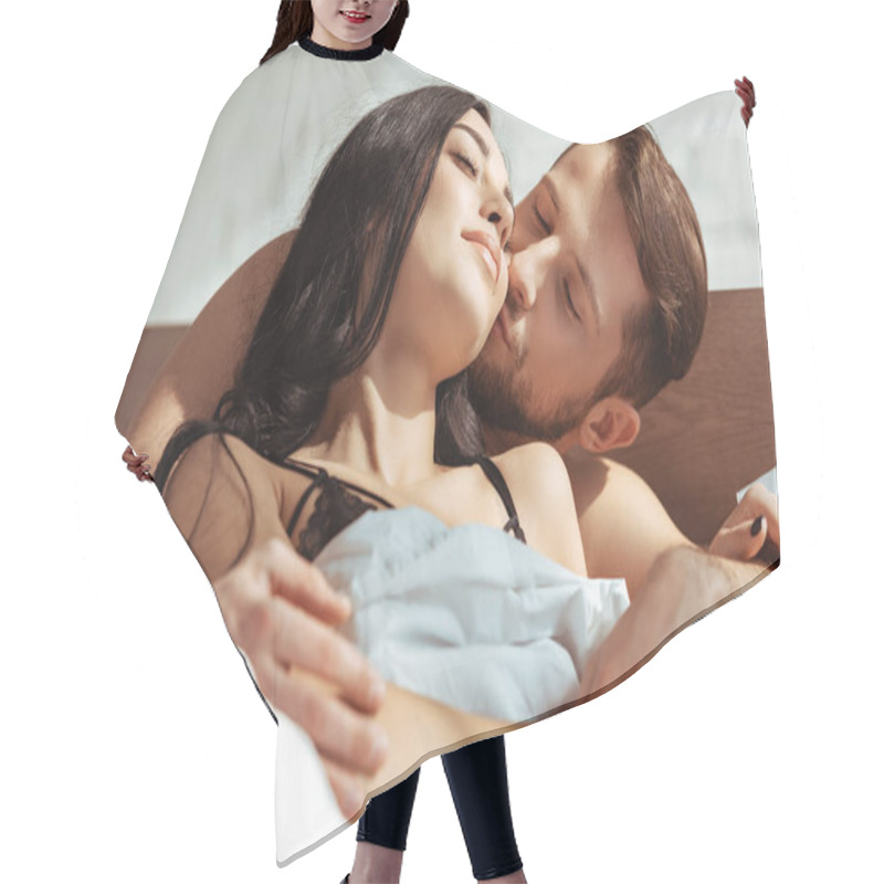 Personality  good-looking man kissing beautiful and brunette woman in bedroom  hair cutting cape