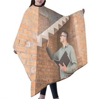 Personality  Real Estate Agent In Eyeglasses Holding Folder And Touching Stairs In House With Unfinished Interior Hair Cutting Cape