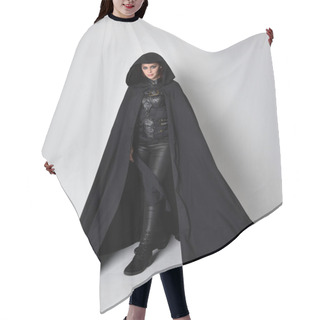 Personality  Fantasy Portrait Of A Woman With Red Hair Wearing Dark Leather Assassin Costume With Long Black Cloak. Full Length Standing Pose  Isolated Against A Studio Background. Hair Cutting Cape