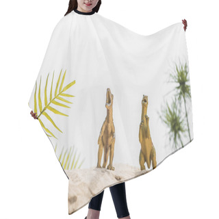 Personality  Selective Focus Of Toy Dinosaurs Roaring On Sand Dune With Tropical Leaves Hair Cutting Cape