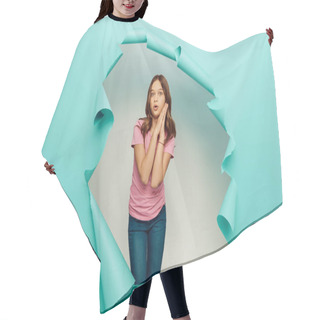 Personality  Shocked Preteen Girl In Pink T-shirt Looking At Camera During International Children Day Celebration While Standing Behind Hole In Blue Paper Background Hair Cutting Cape