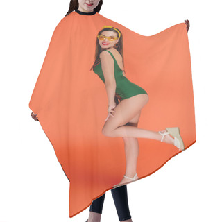 Personality  Side View Of Woman Raising Leg, Smiling And Looking At Camera On Orange Background Hair Cutting Cape