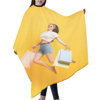 Personality  Full Length View Of Smiling Stylish Summer Brunette Girl Jumping With Shopping Bags On Yellow Background Hair Cutting Cape