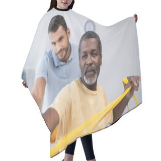 Personality  Mature African American Man Training With Elastics Near Blurred Trainer In Rehab Center Hair Cutting Cape